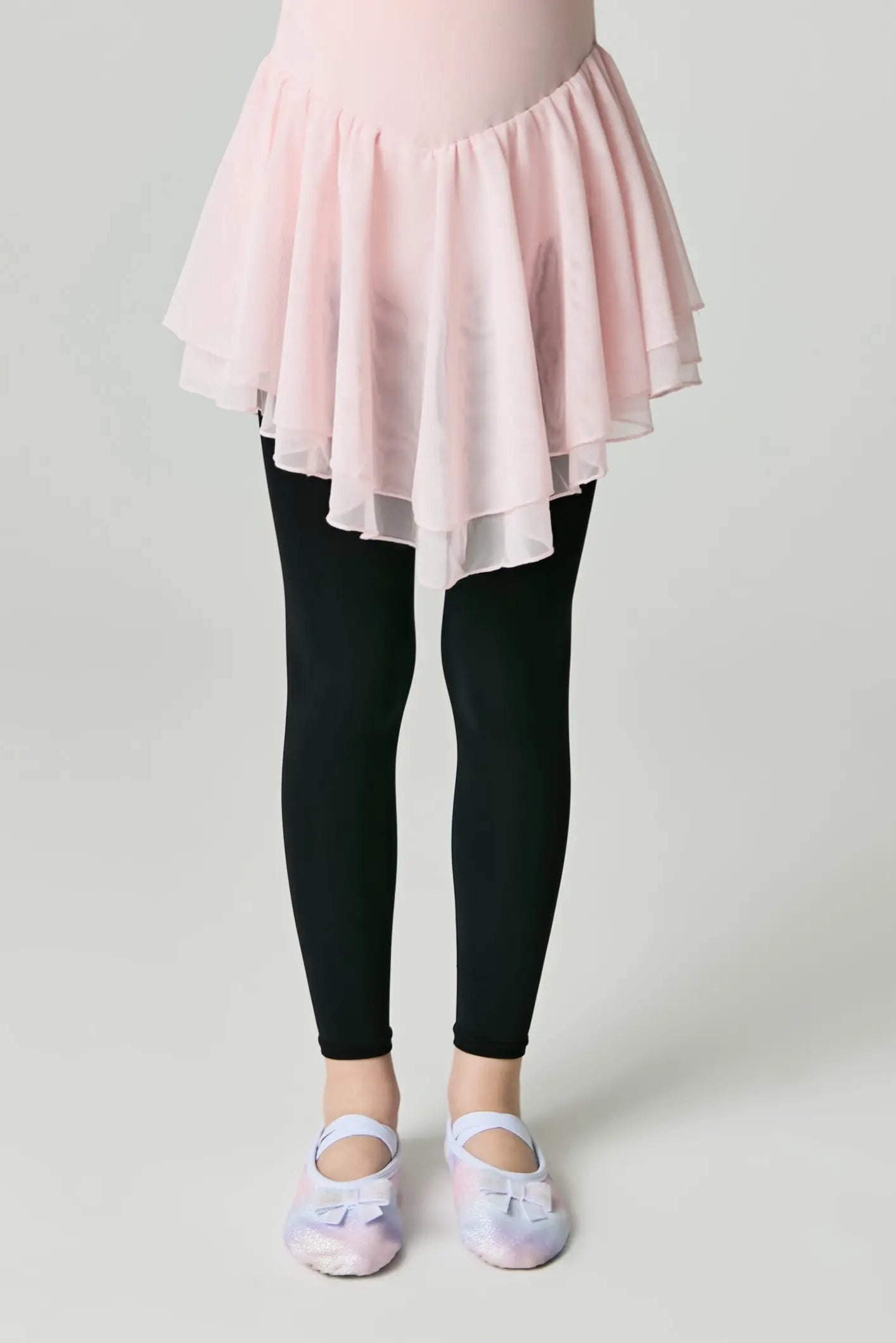 Person wearing a pink skirt over black leggings on a plain background #color_nero-black