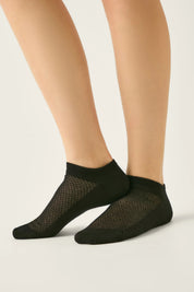 Black fishnet socks worn by a person on a light background #color_black