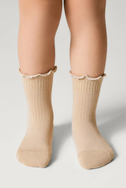 Beige socks with ruffled top worn by a person on a light gray background #color_beige