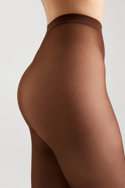 Close-up side view of a model wearing sheer brown hosiery against a light gray studio background.