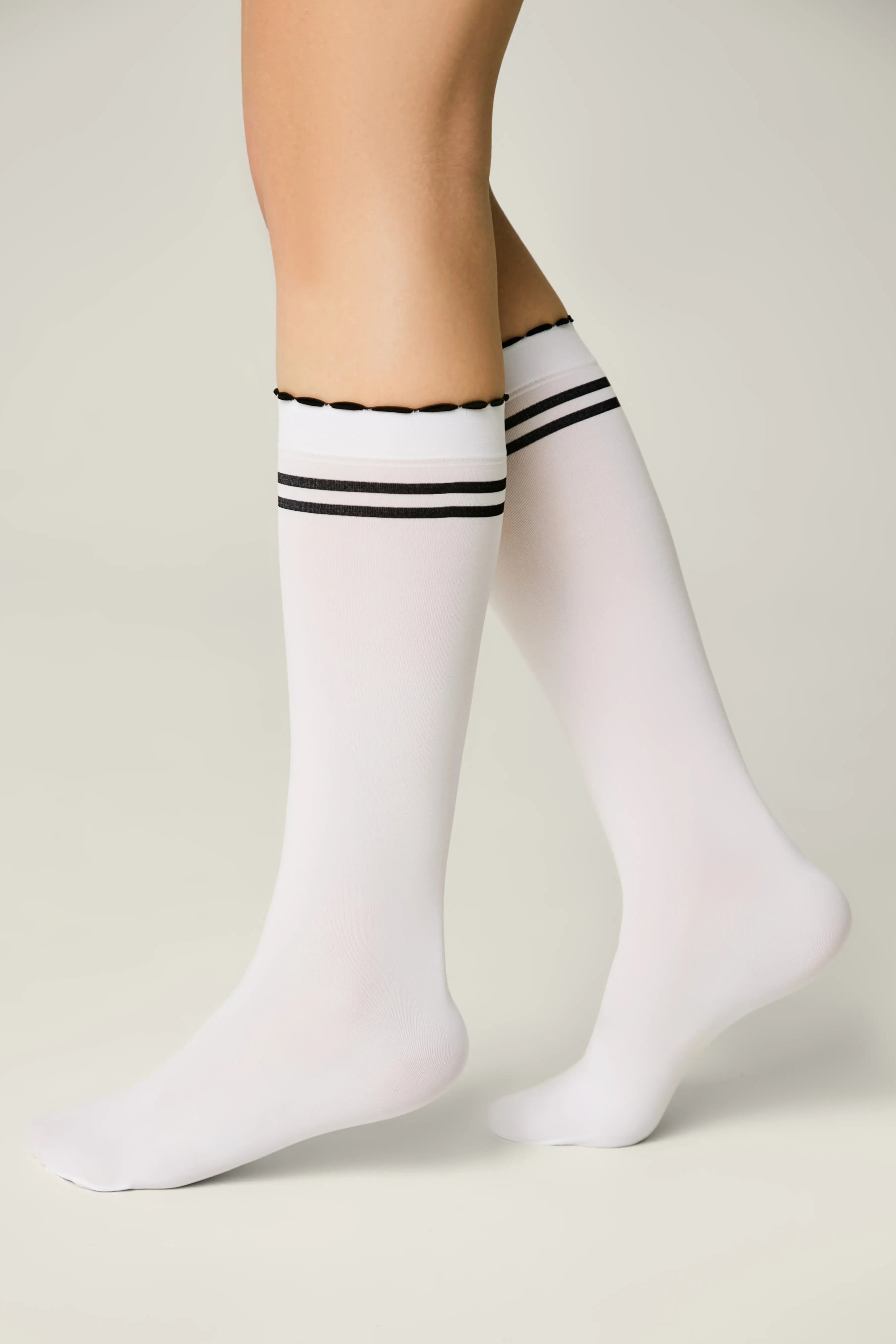 White knee-high socks with black stripes worn by a person on a light background