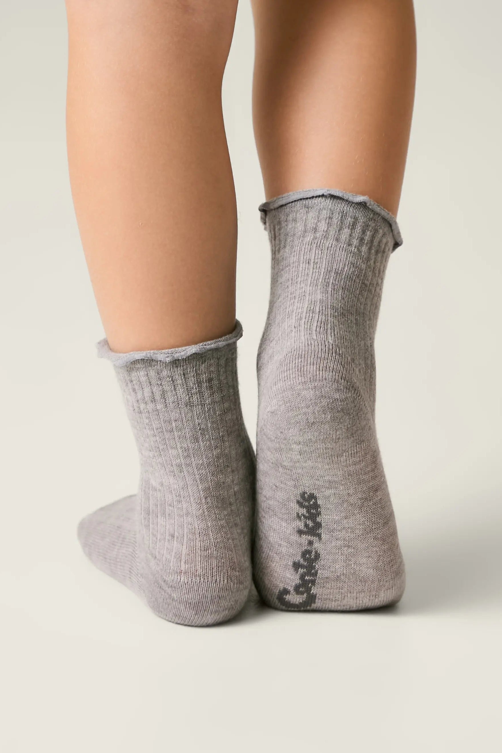 Gray socks worn by a person on a light gray background #color_gray