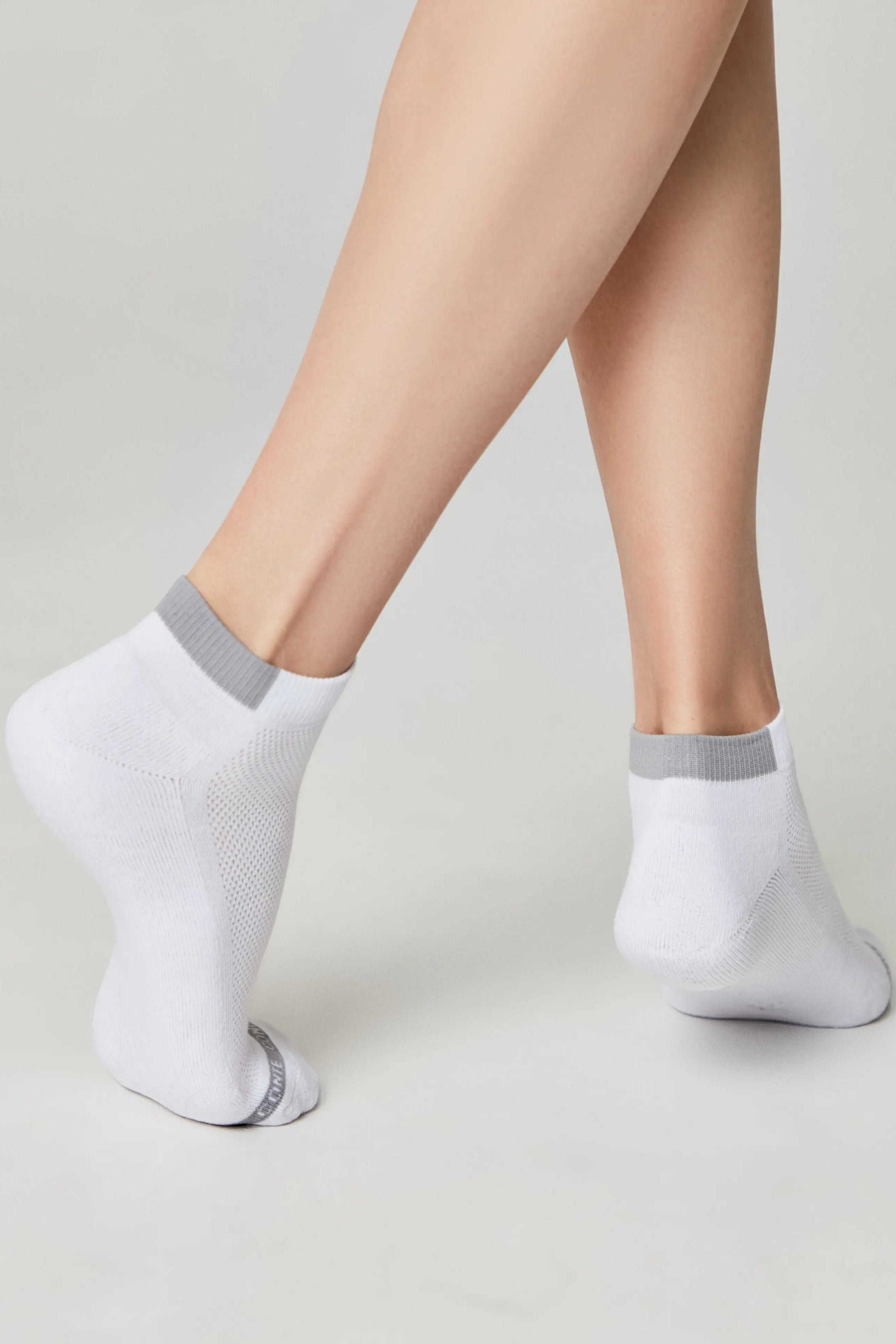 White ankle socks with gray accents worn by a person on a light gray background #color_white