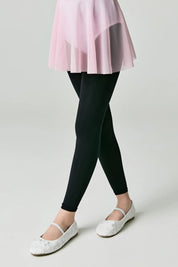 Person wearing black leggings with a light pink skirt and white shoes on a plain background #color_nero-black