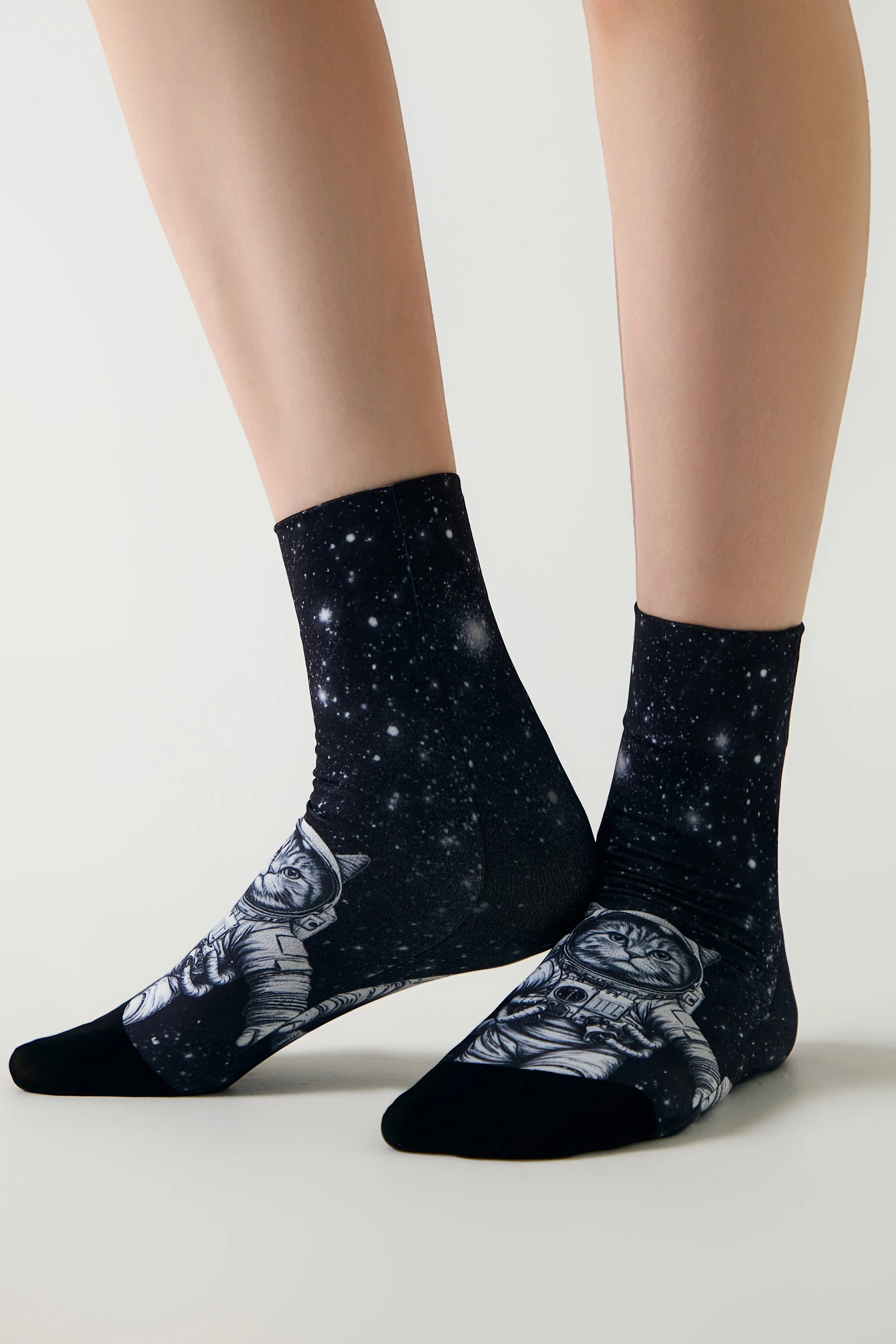 Black socks with a white design worn by a person on a light gray background