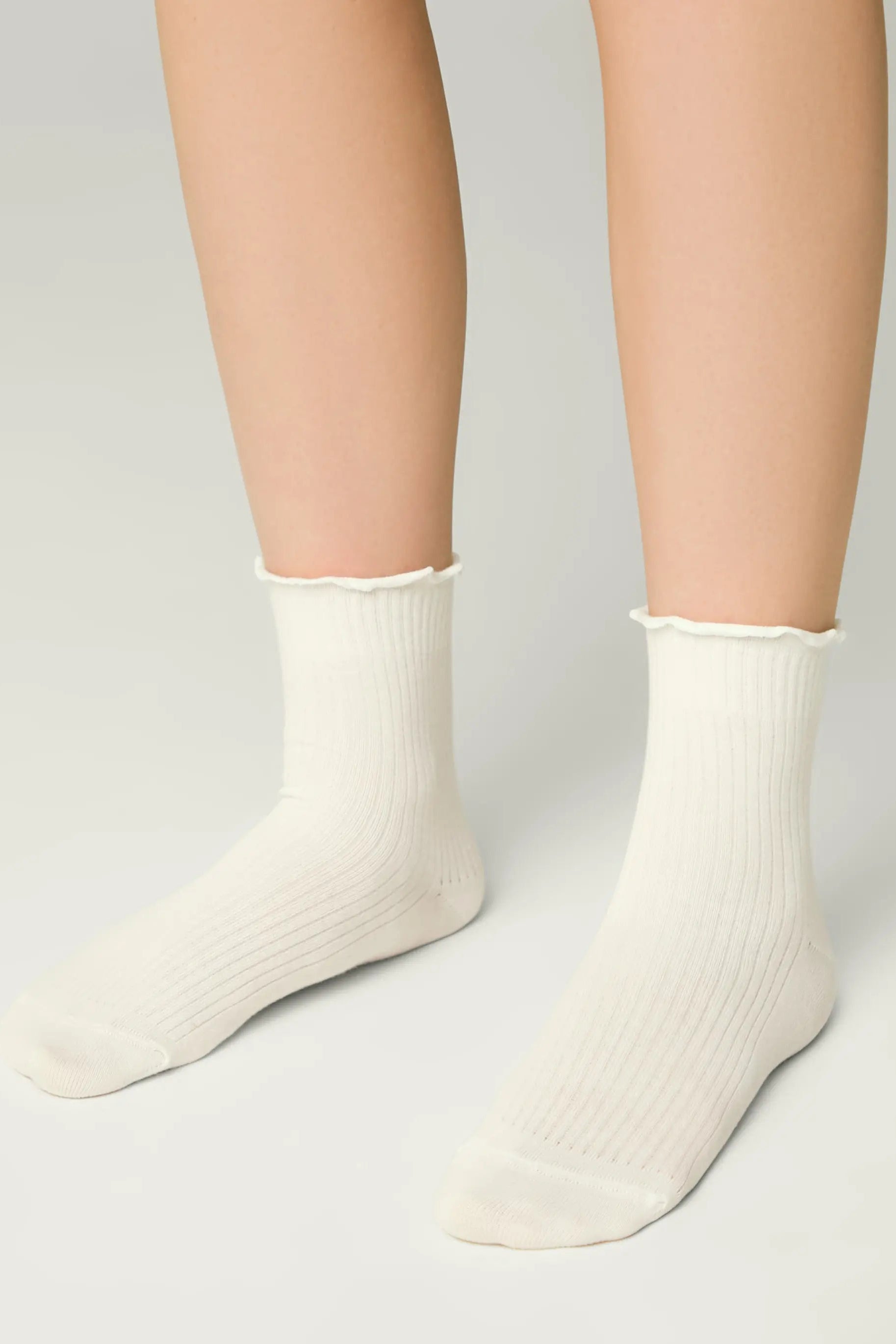 White socks worn by a person on a light gray background #color_milky