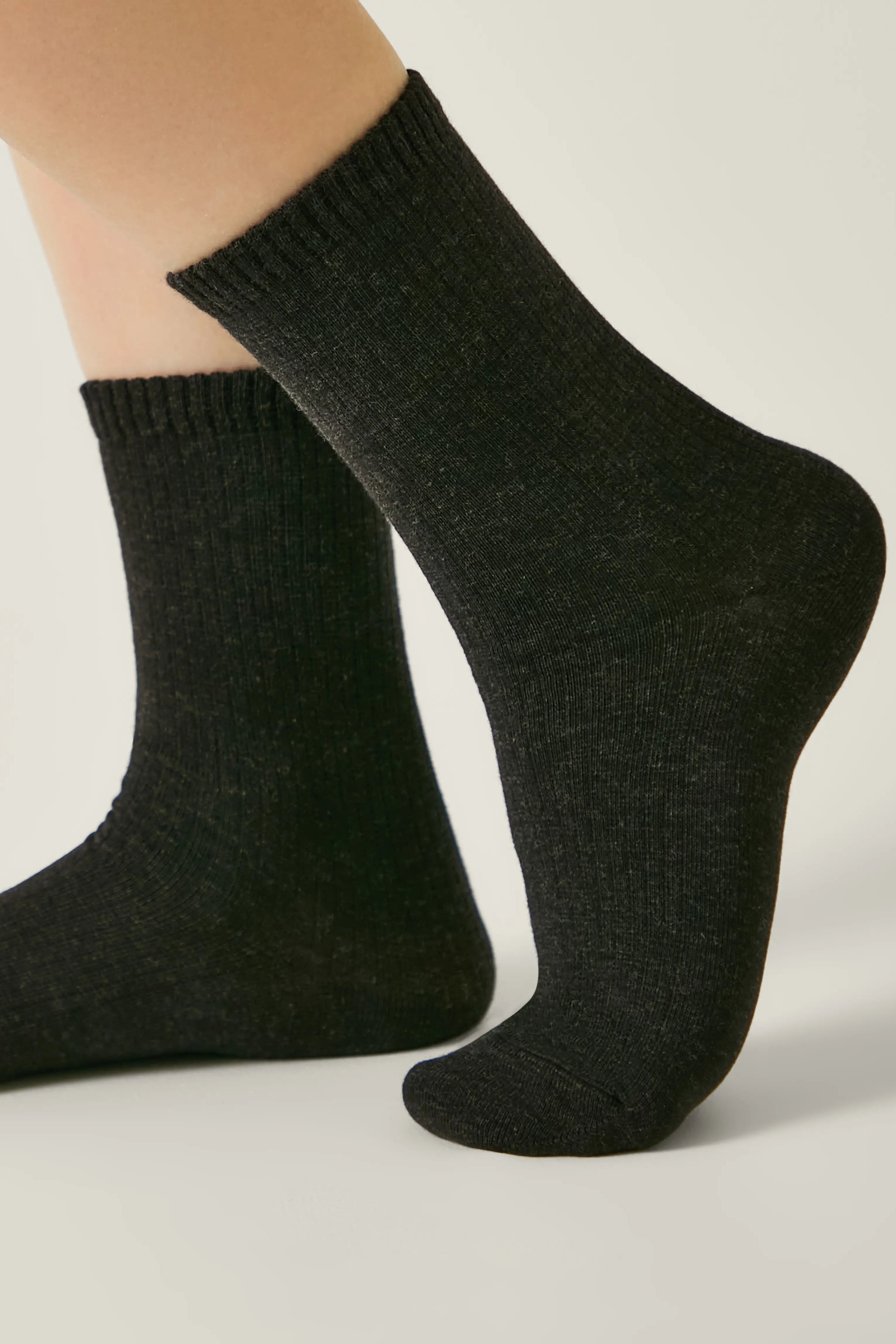 Dark gray socks worn by a person on a light background #color_black