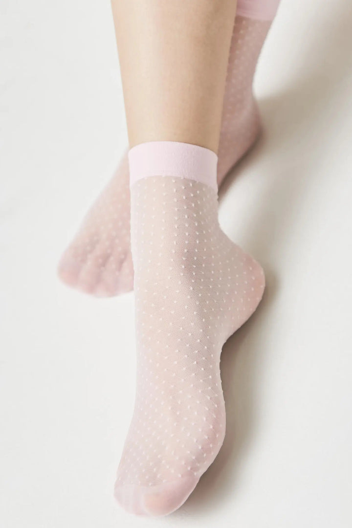 Pink polka dot socks worn by a person on a light background #color_light-pink