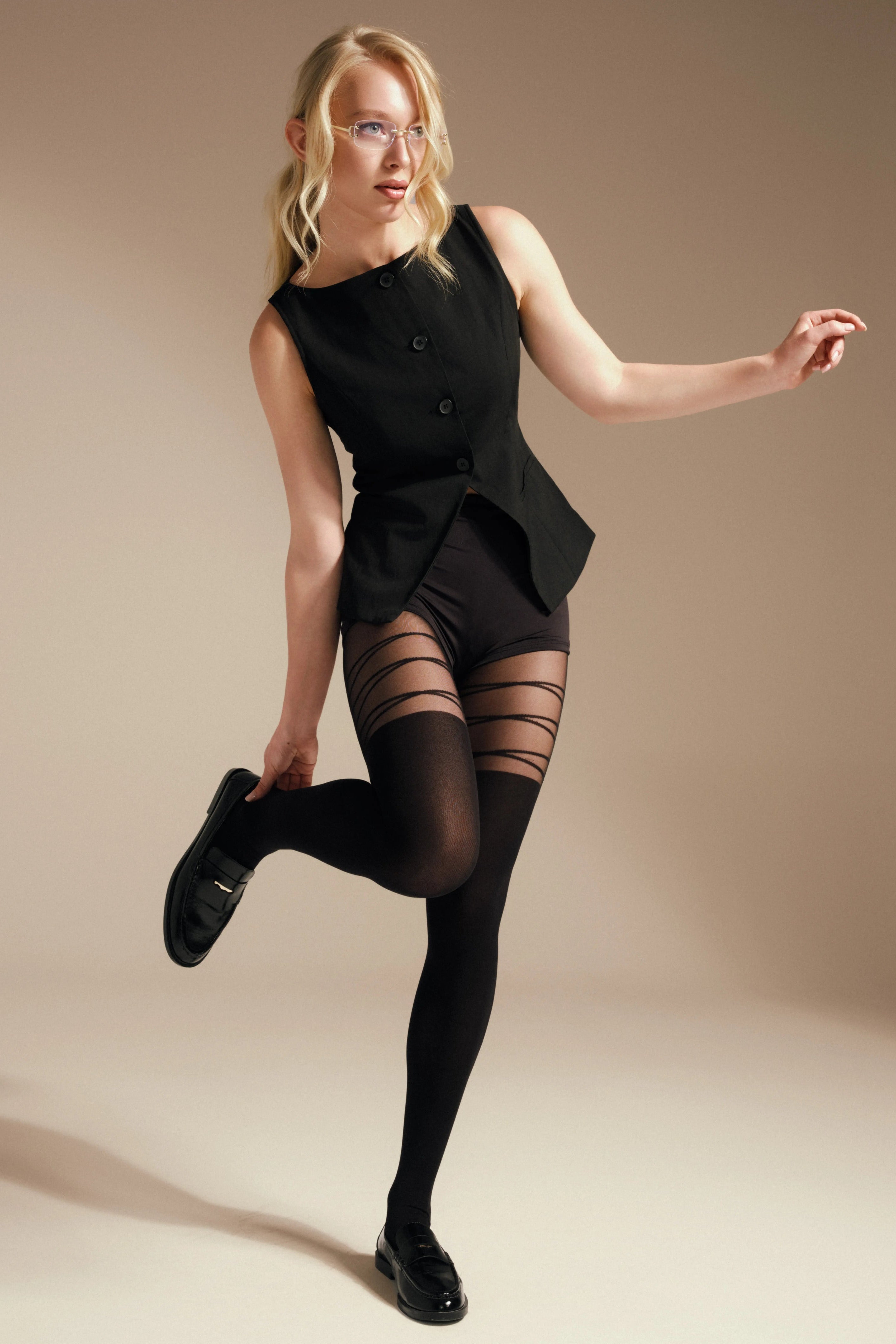 Woman wearing a black outfit with sheer stockings against a beige background #color_nero-black