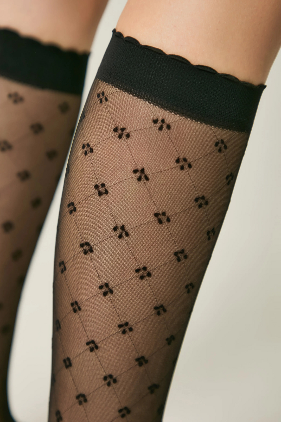 Patterned sheer stockings with black top band on a neutral background #color_nero-black