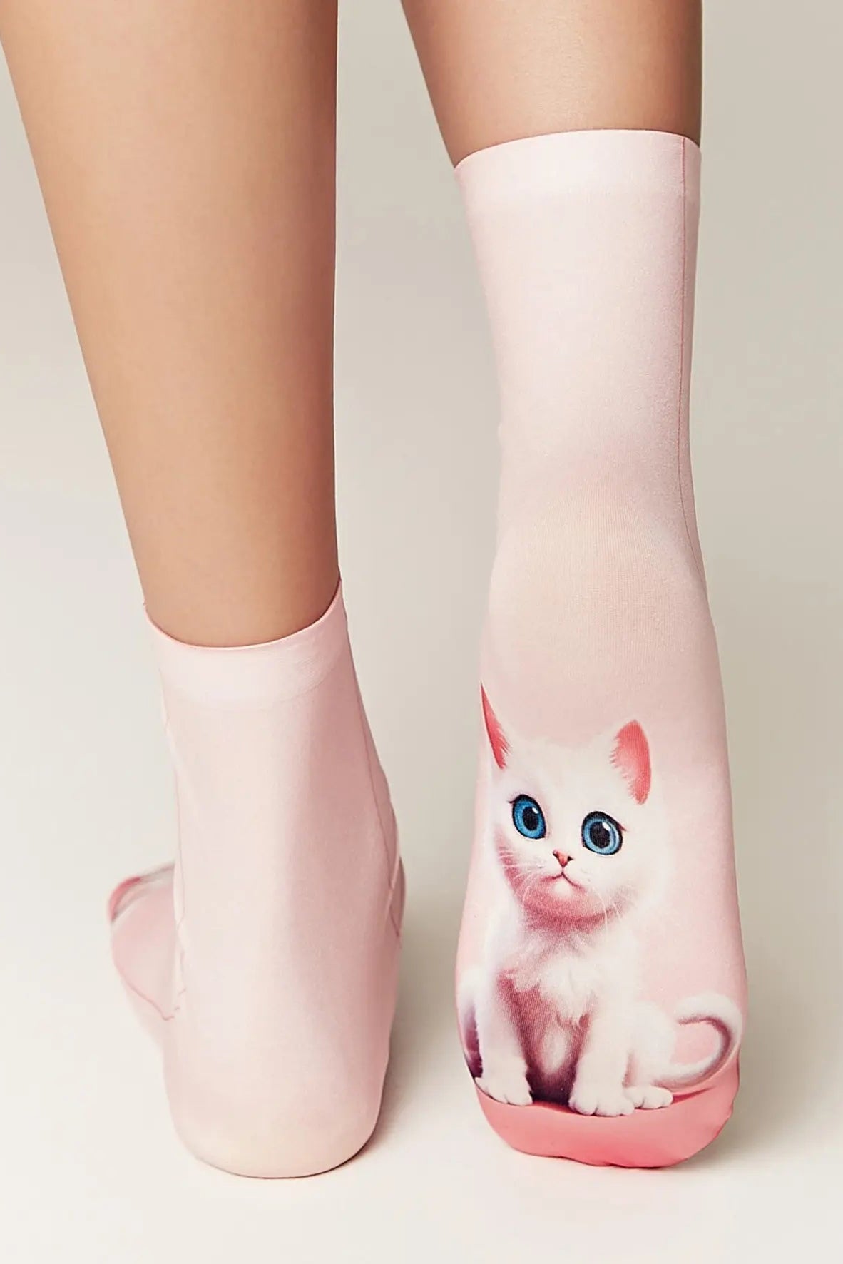 Pink socks with a kitten design worn by a person on a light background
