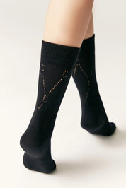 Black socks with star patterns worn by a person on a white background #color_black