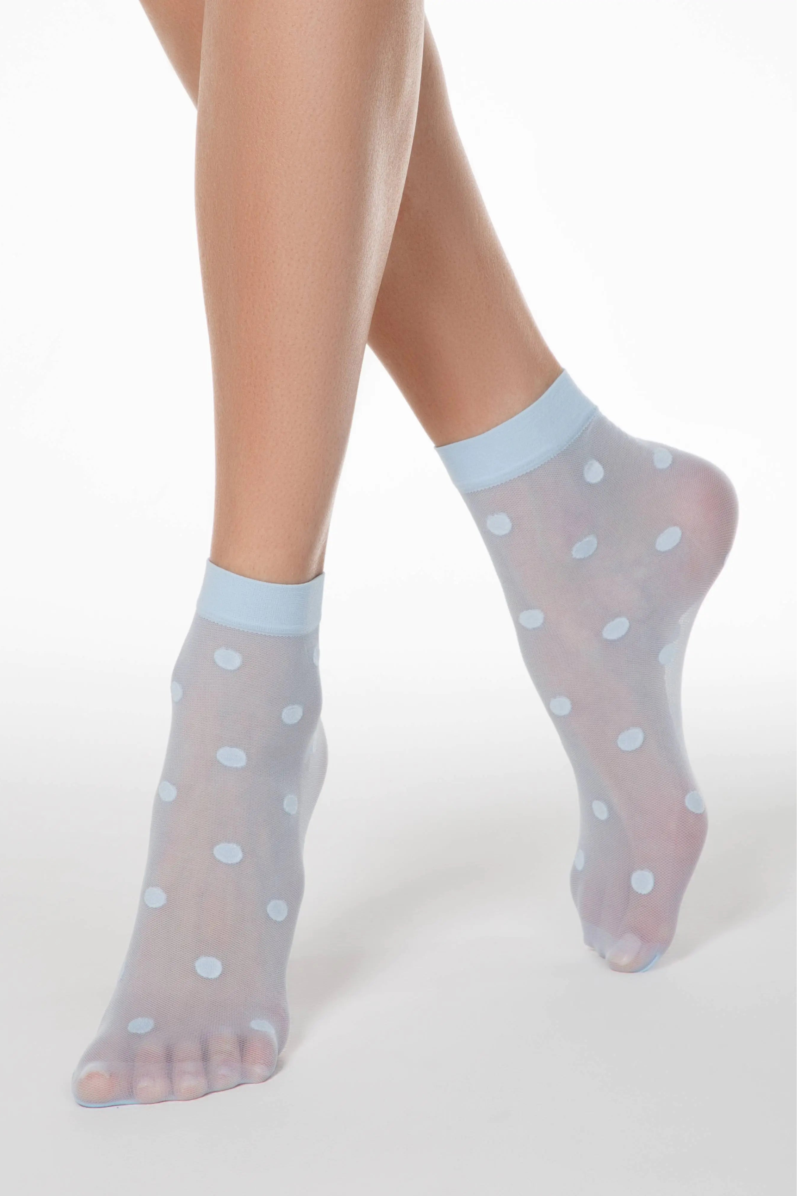 Sheer socks with polka dots worn by a person on a white background #color_light-blue
