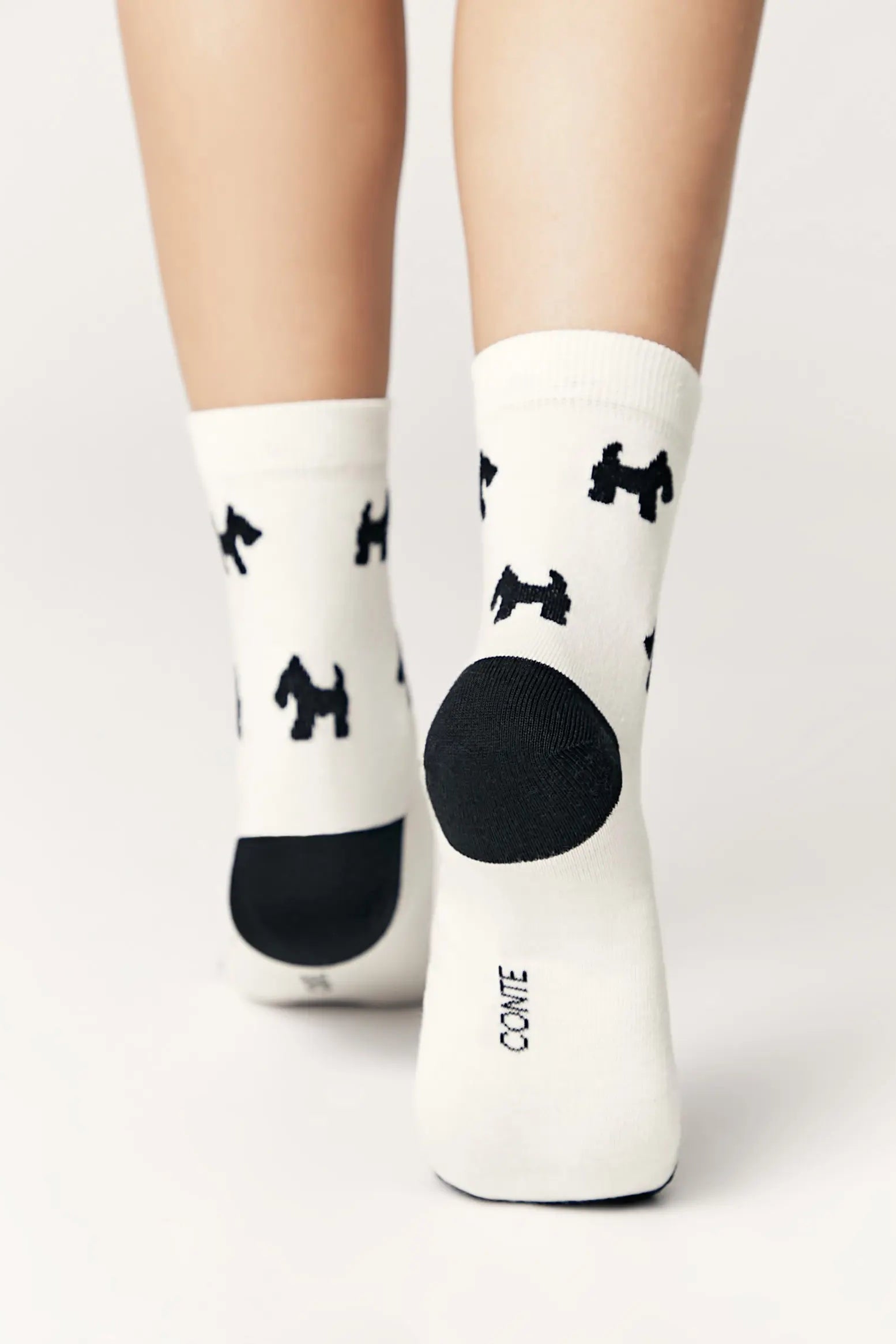 White socks with black dog prints and a large black dot on a white background #color_milk