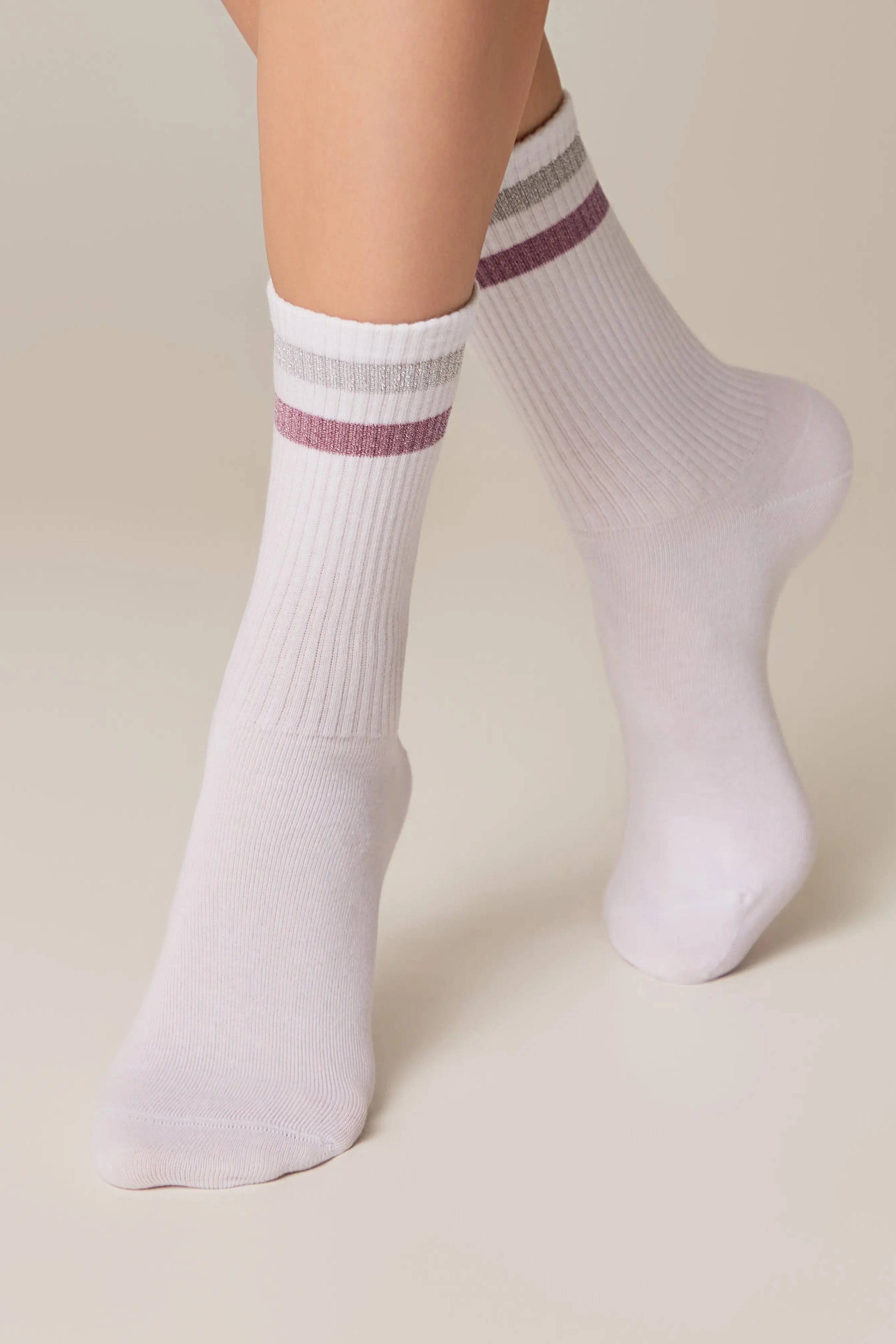 White socks with purple stripes worn by a person on a beige background #color_light-gray