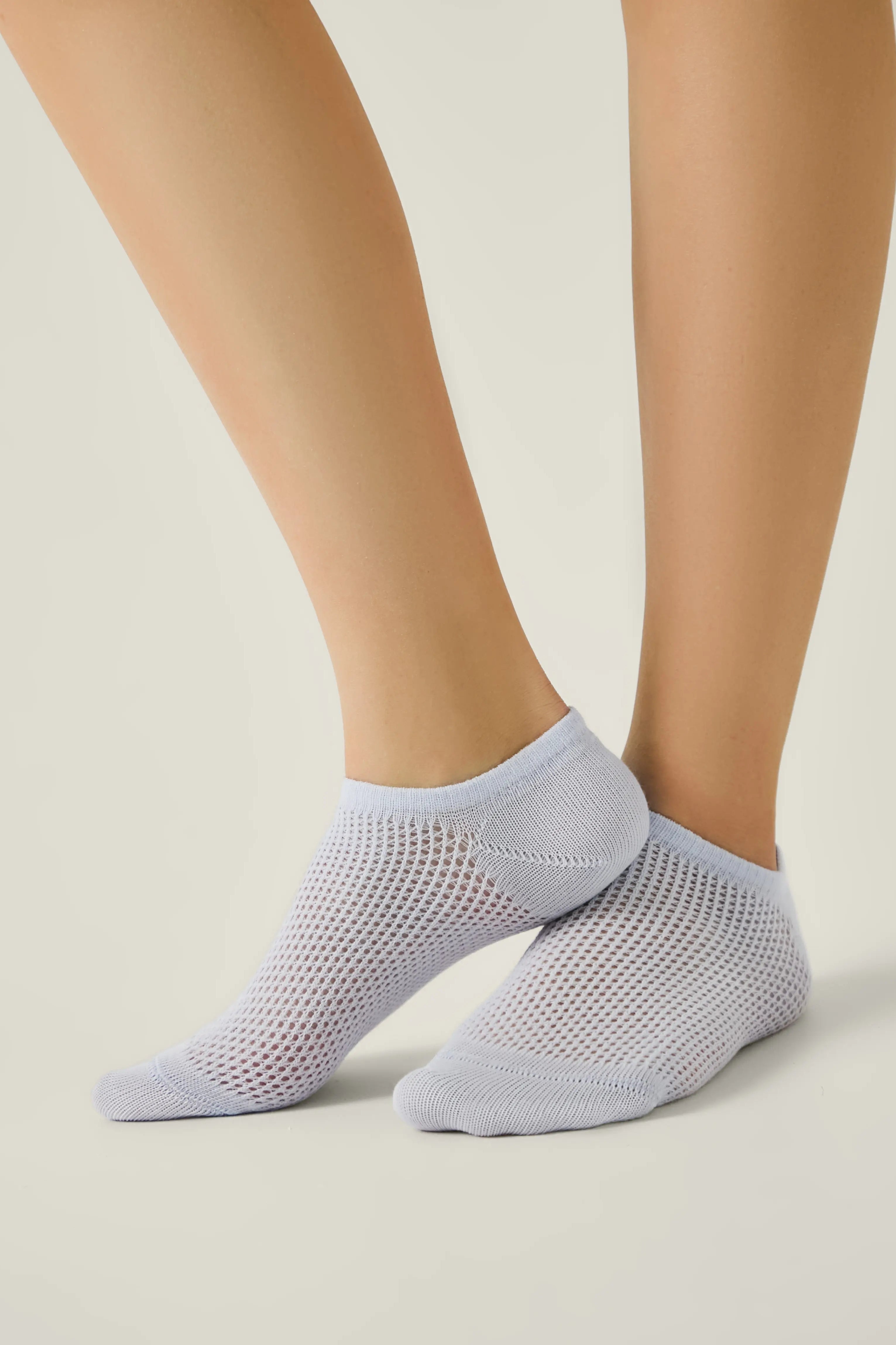 Light gray ankle socks worn by a person on a neutral background #color_pale-purple