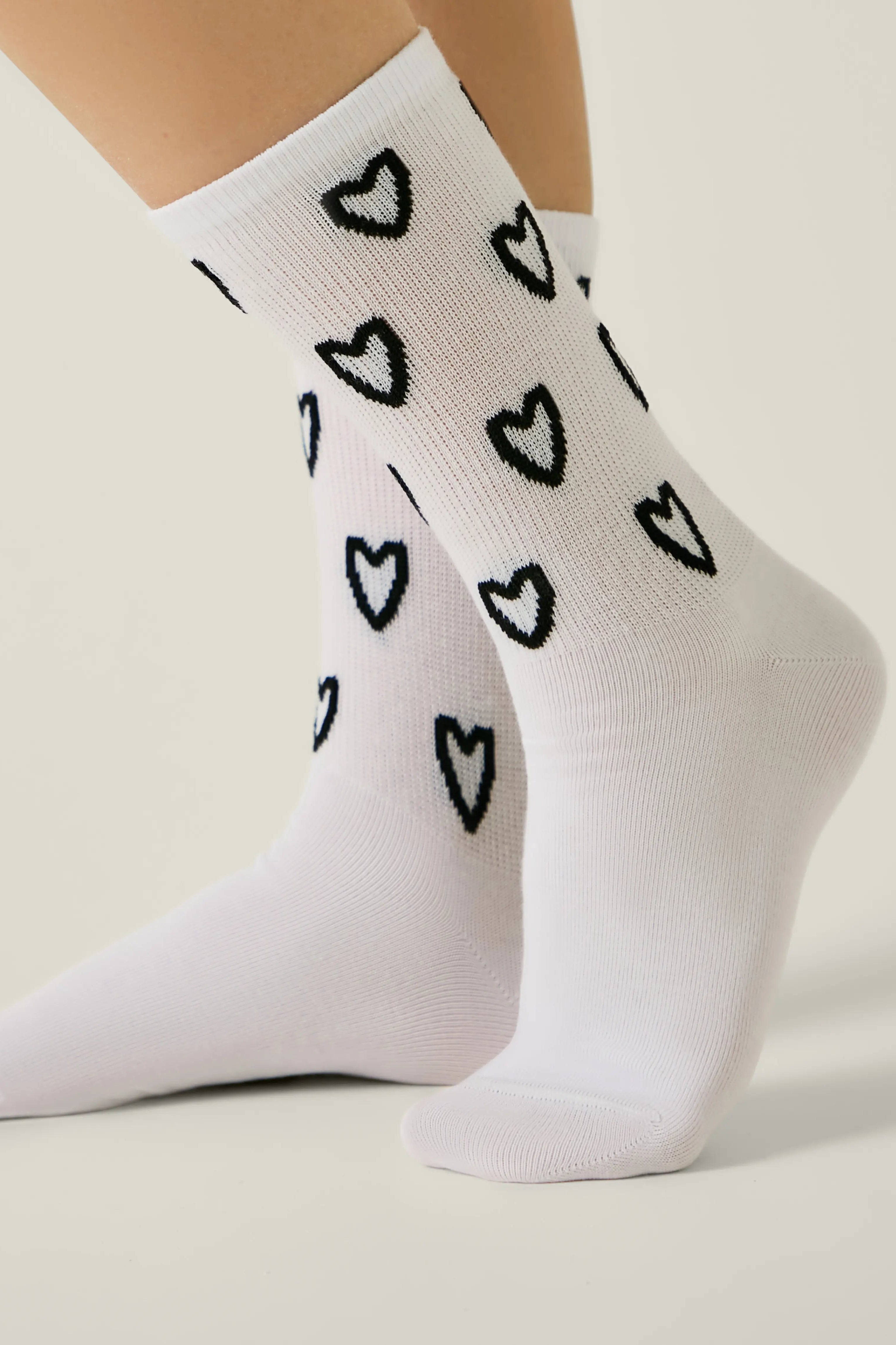 White socks with black heart patterns worn by a person on a light background #color_white
