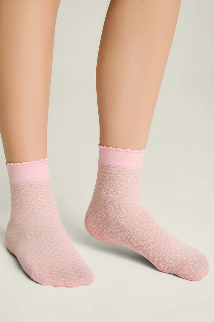 Pink socks worn by a person on a light gray background #color_light-pink