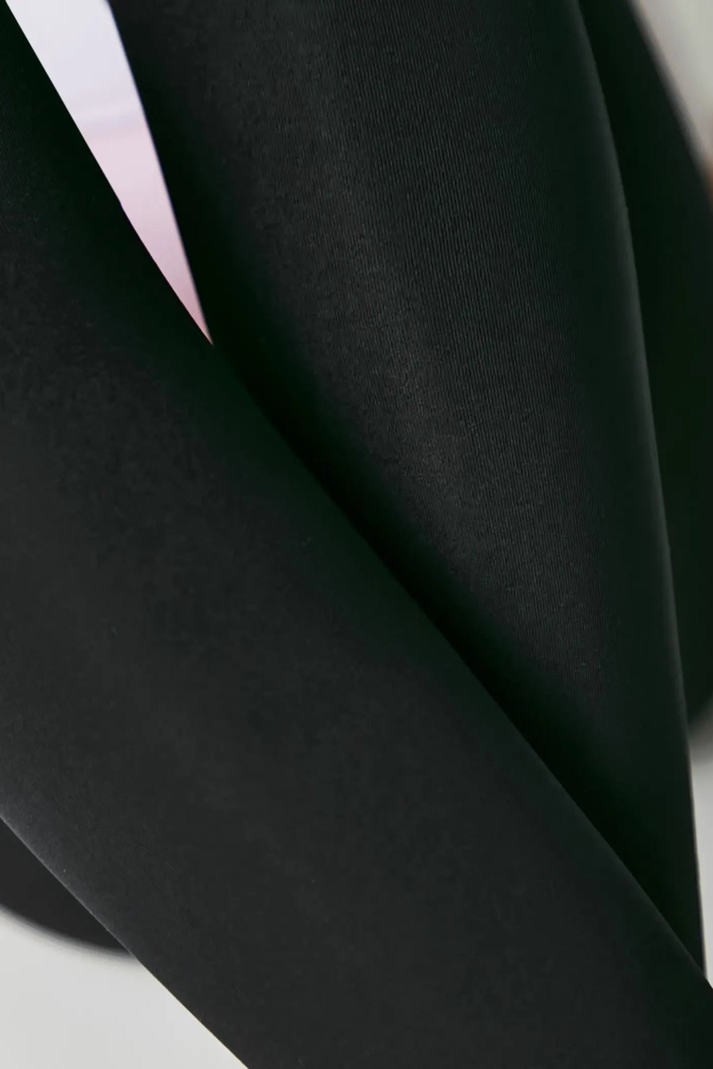 Close-up of black fabric with a blurred background #color_nero-black