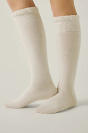 Beige knee-high socks with lace top on a light gray background