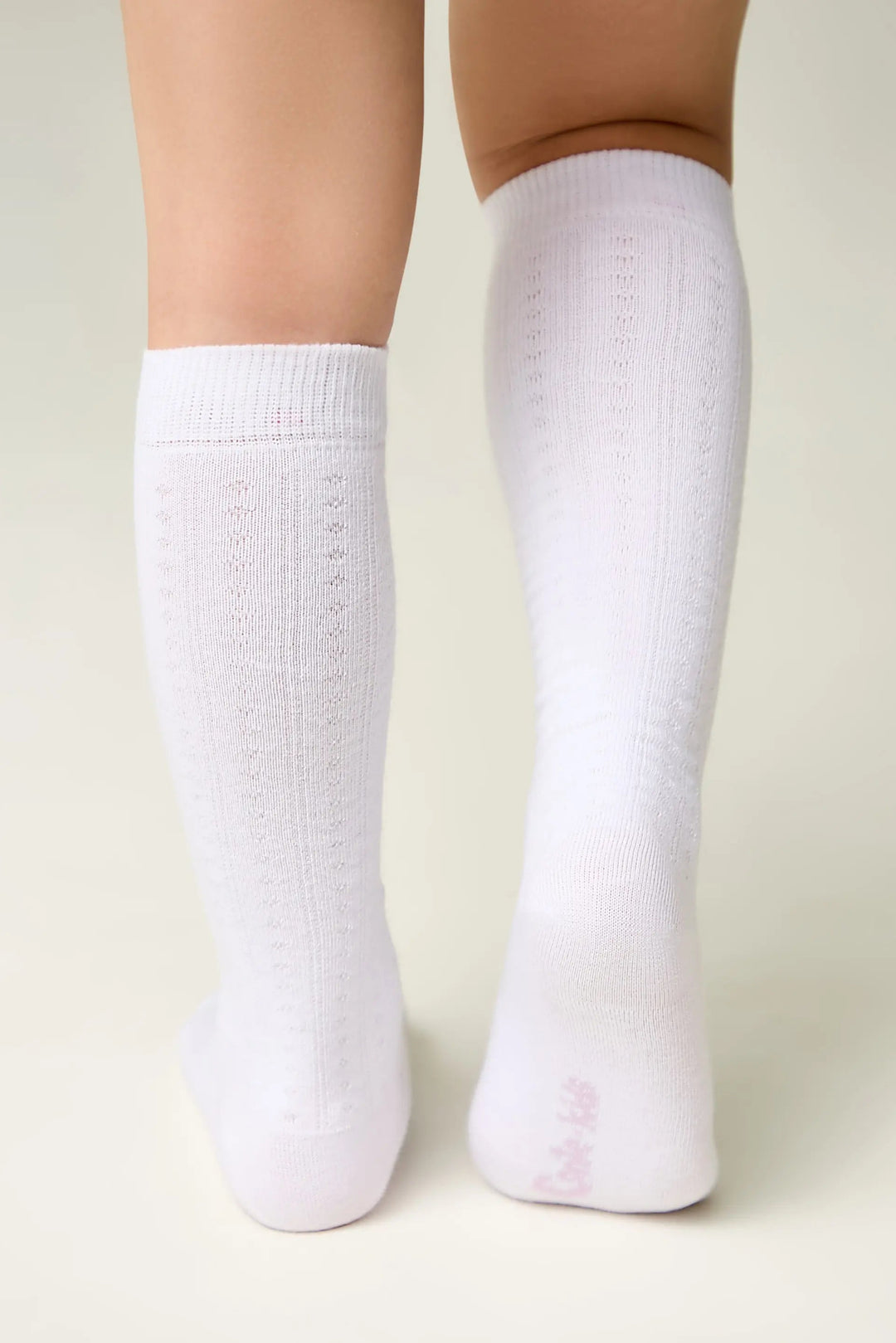 White knee-high socks worn by a person on a light background #color_white