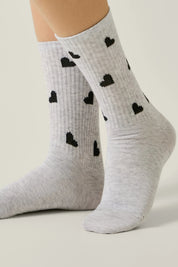 Gray socks with black heart patterns worn by a person on a light background #color_light-gray