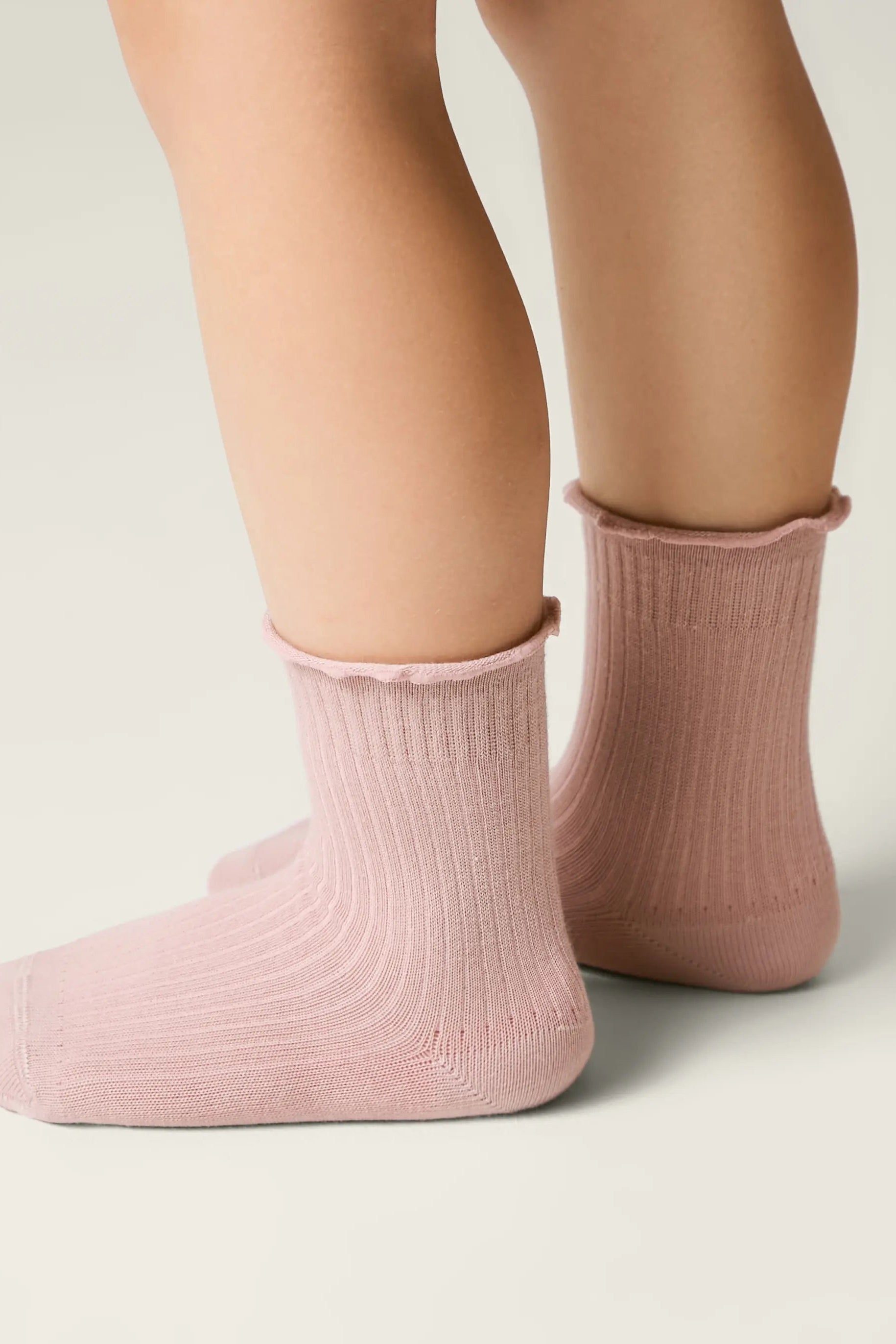 Pink socks worn by a person on a neutral background #color_ash-pink