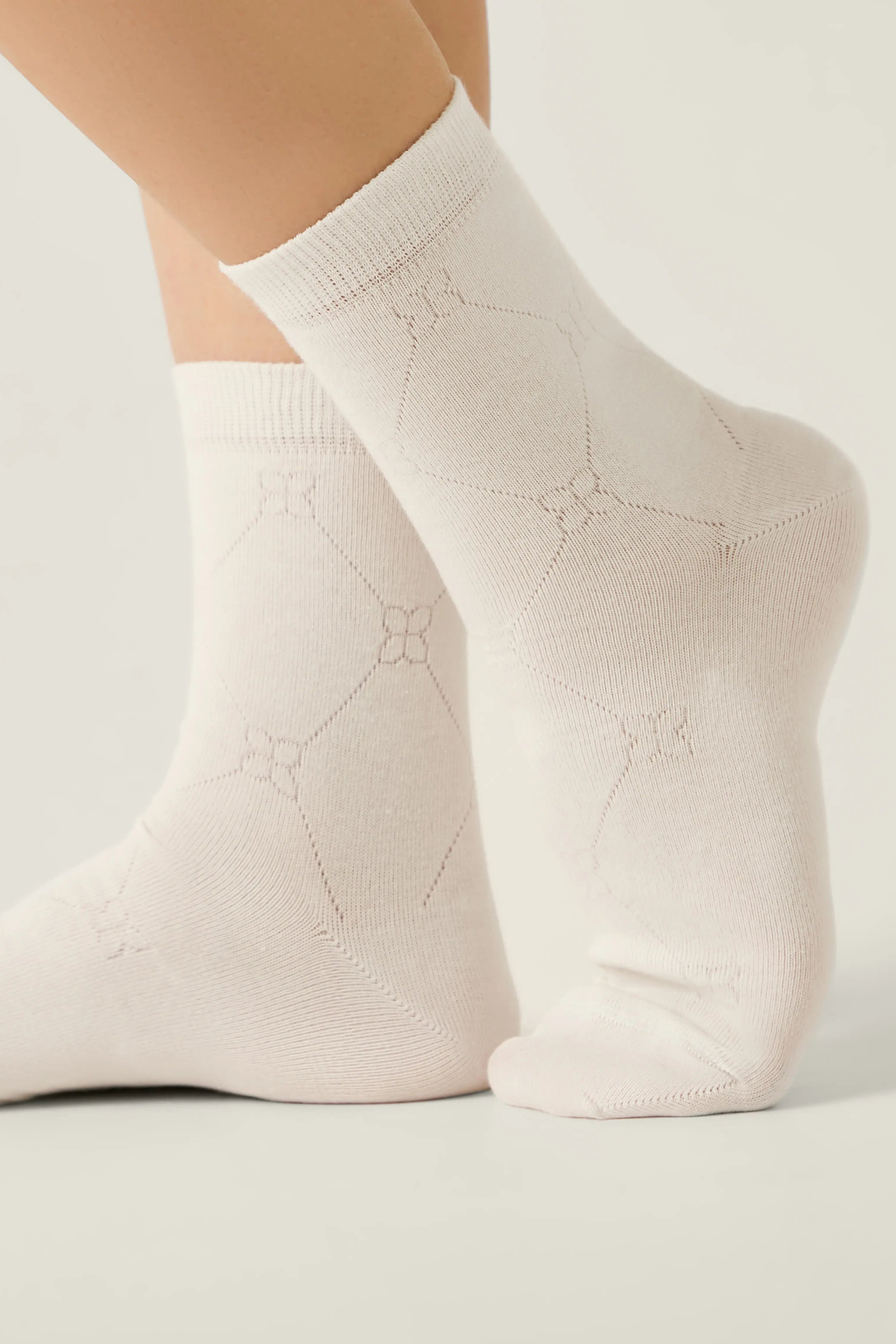 White socks with subtle pattern worn by a person on a light background #color_milky