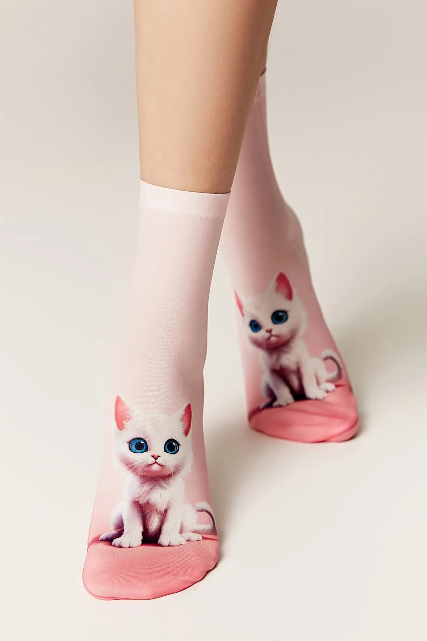 Pink socks with cat designs worn by a person on a light background