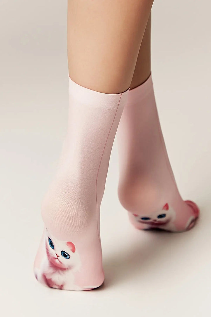 Pink cat-themed socks worn by a person on a light background