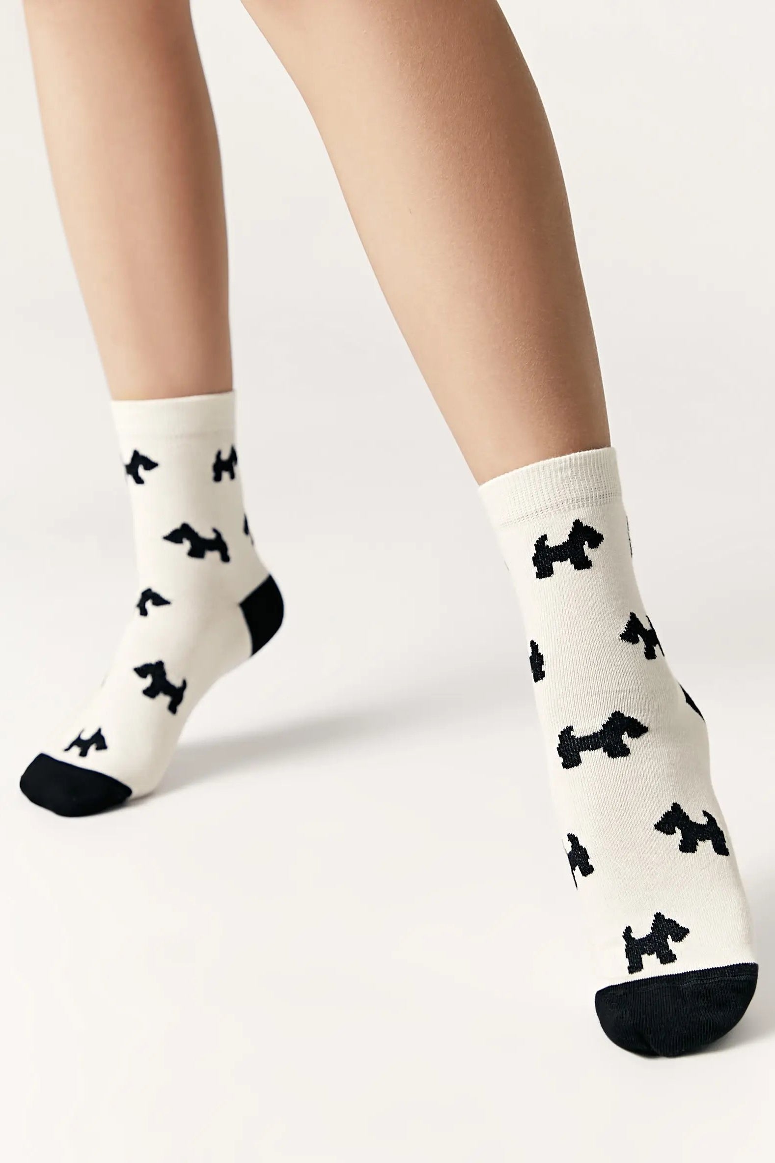 White socks with black dog pattern worn by a person on a white background #color_milk