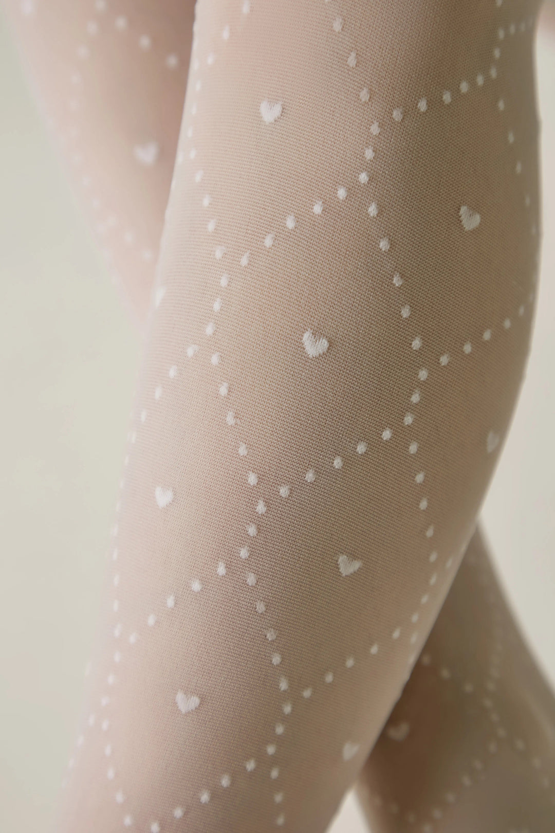 Beige tights with white heart patterns on a neutral background #color_bianco