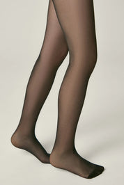 Black tights worn by a person on a plain background #color_nero-black