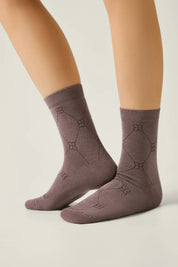 Pair of brown socks with geometric patterns worn by a person on a light background #color_coffee