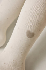 Close-up of beige tights with a heart-shaped spot on a neutral background #color_milky