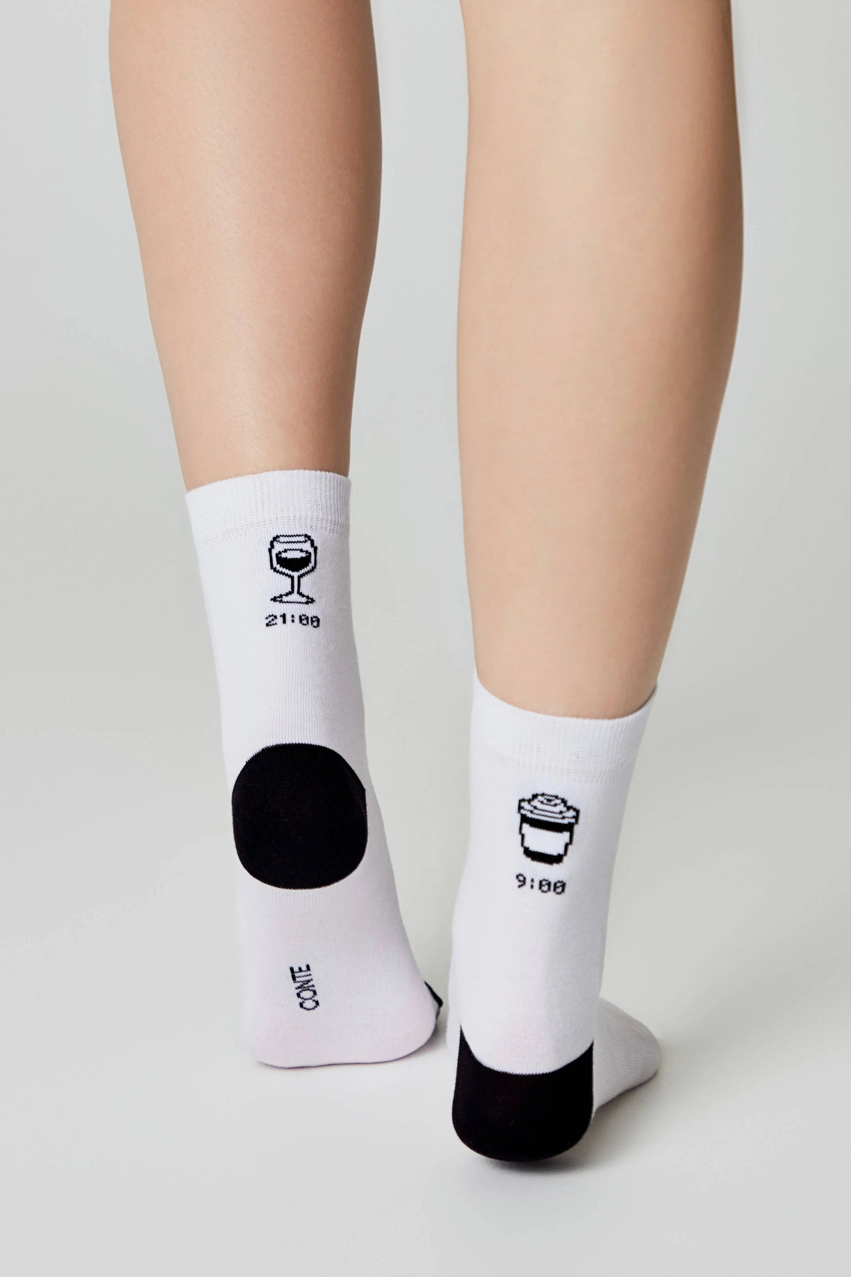 White socks with black designs and text worn by a person on a light gray background