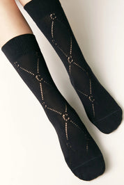 Black socks with geometric pattern worn by a person on a light background #color_black