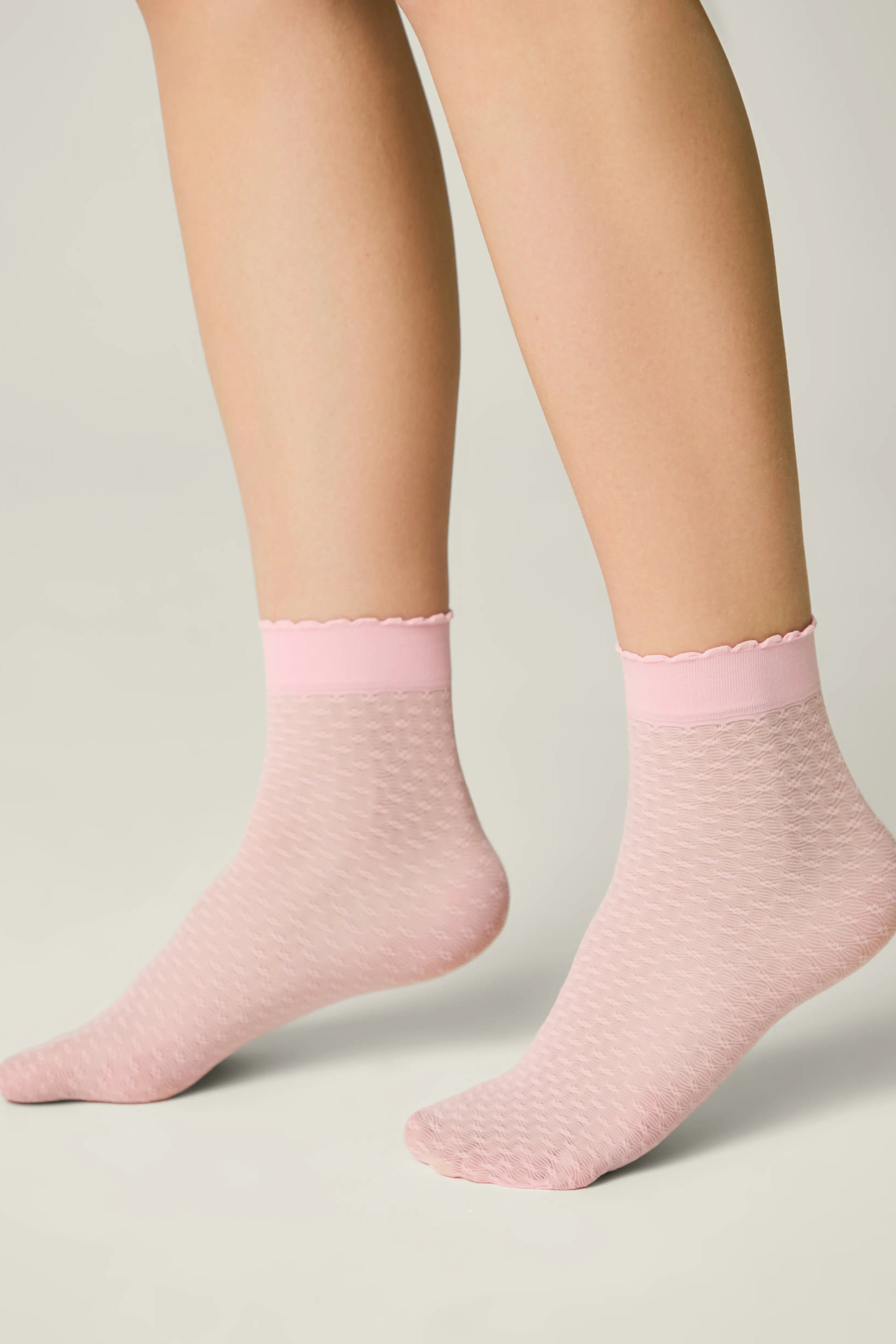 Pink socks worn by a person on a light gray background #color_light-pink