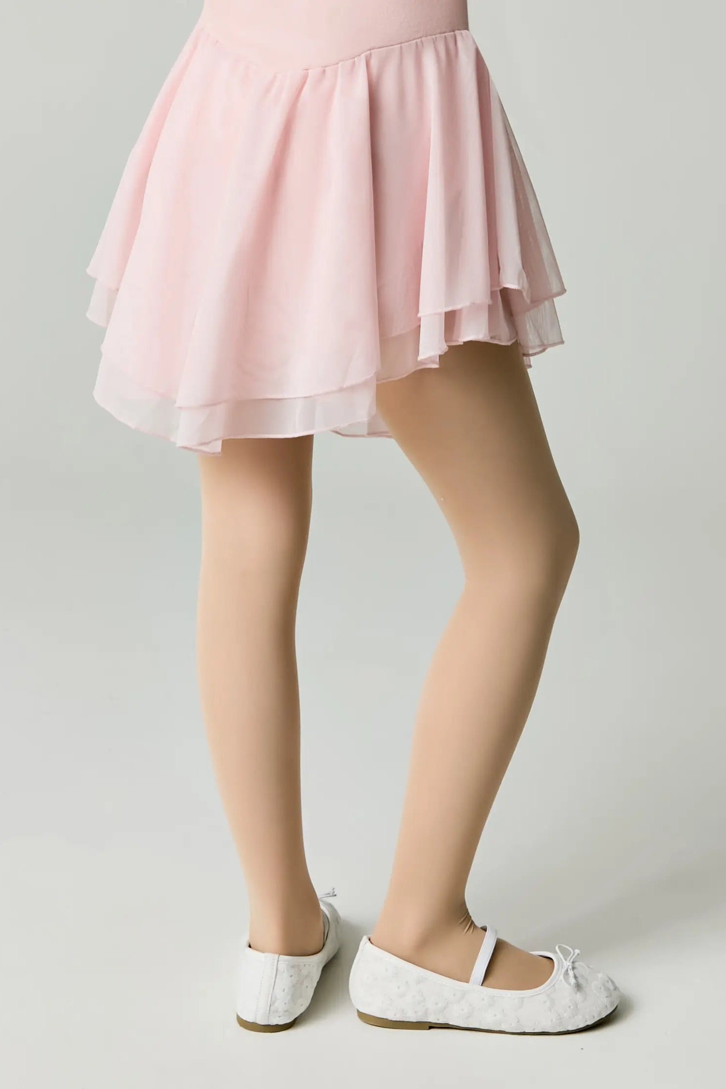 Person wearing a pink skirt and white shoes on a plain background #color_natural-nude