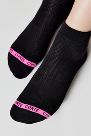 Black ankle socks with pink brand logo on a light gray background #color_black