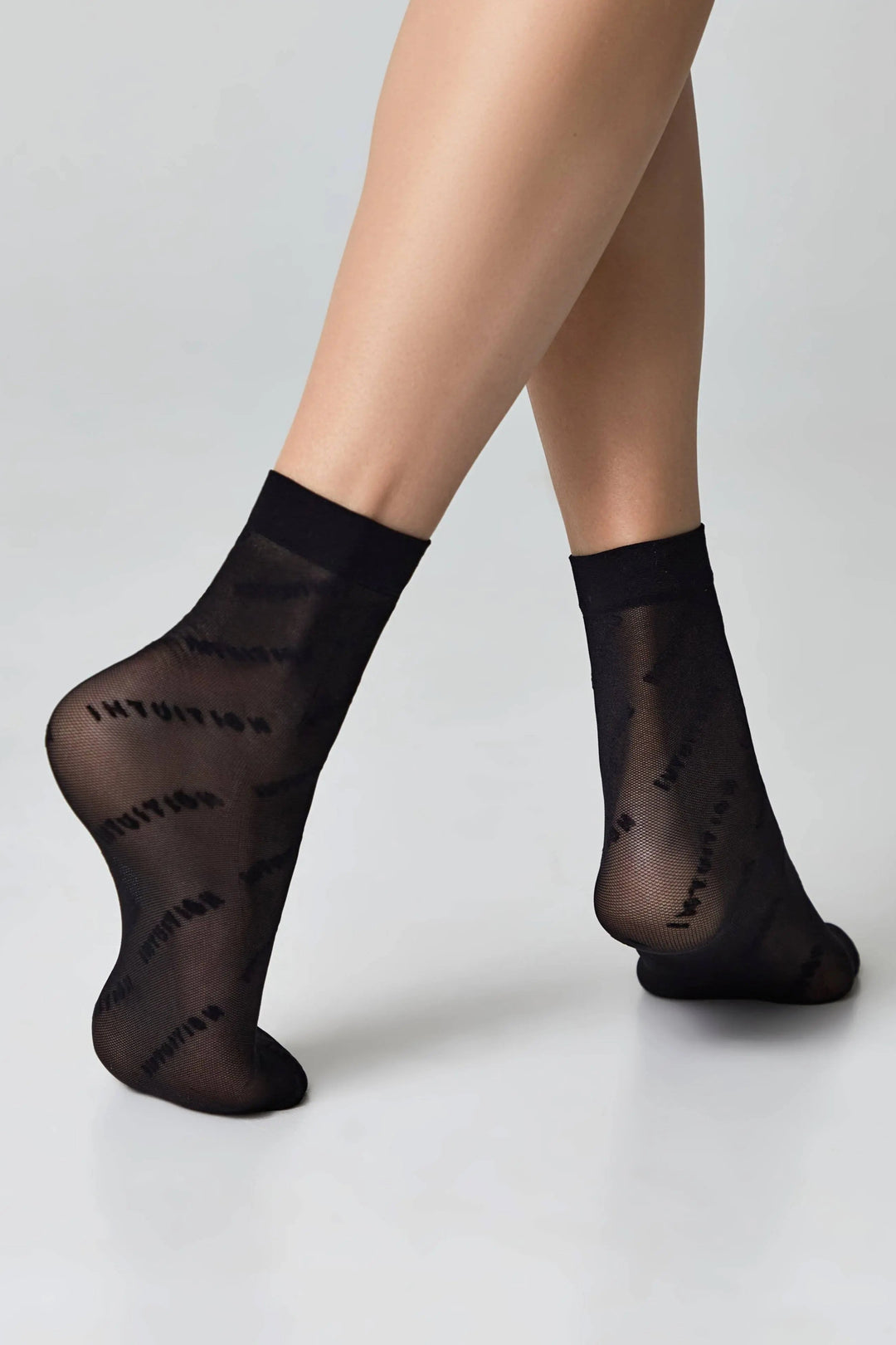 Black sheer socks worn by a person on a light gray background