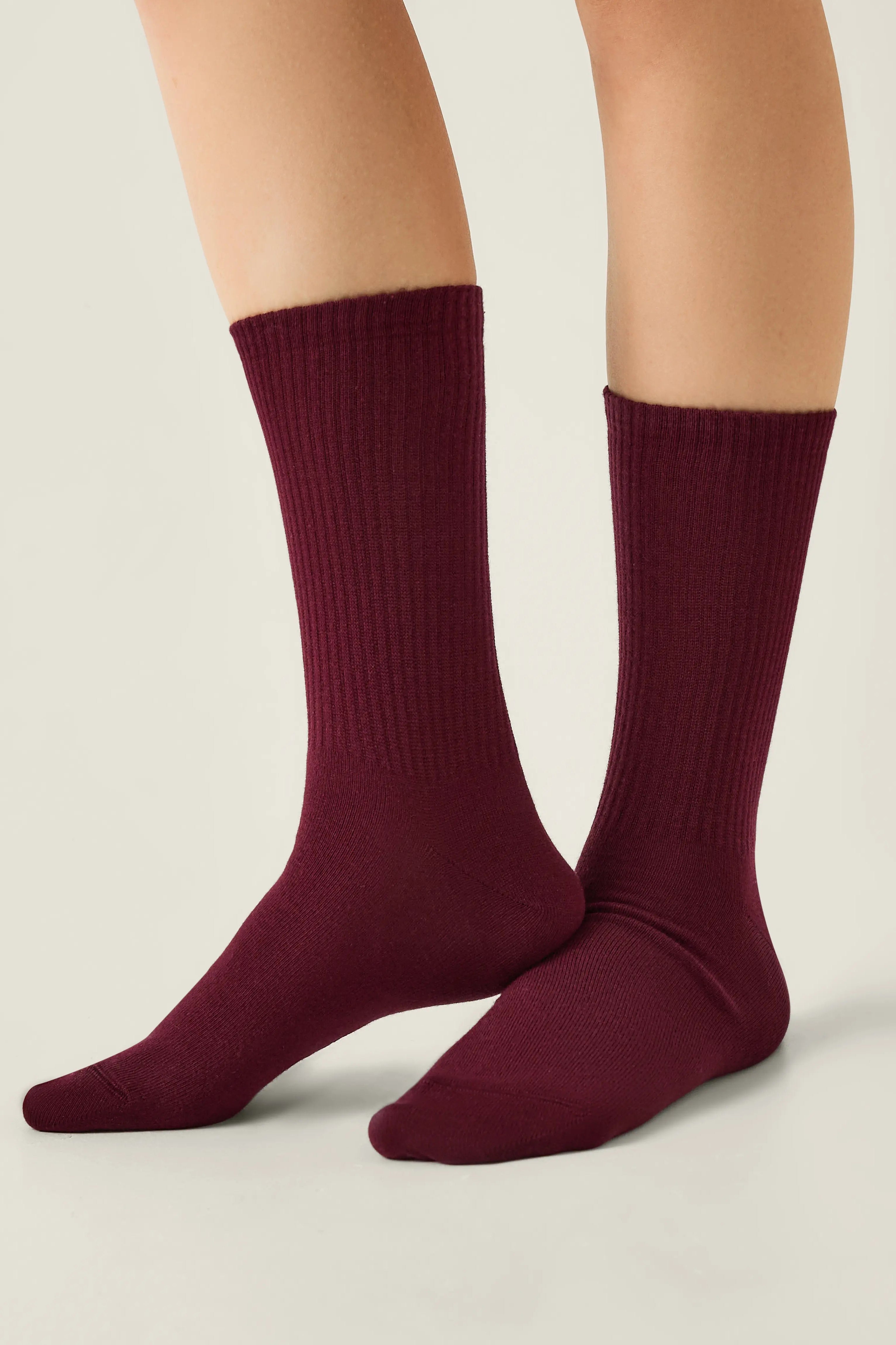 Maroon socks worn by a person on a neutral background #color_dark-bordo